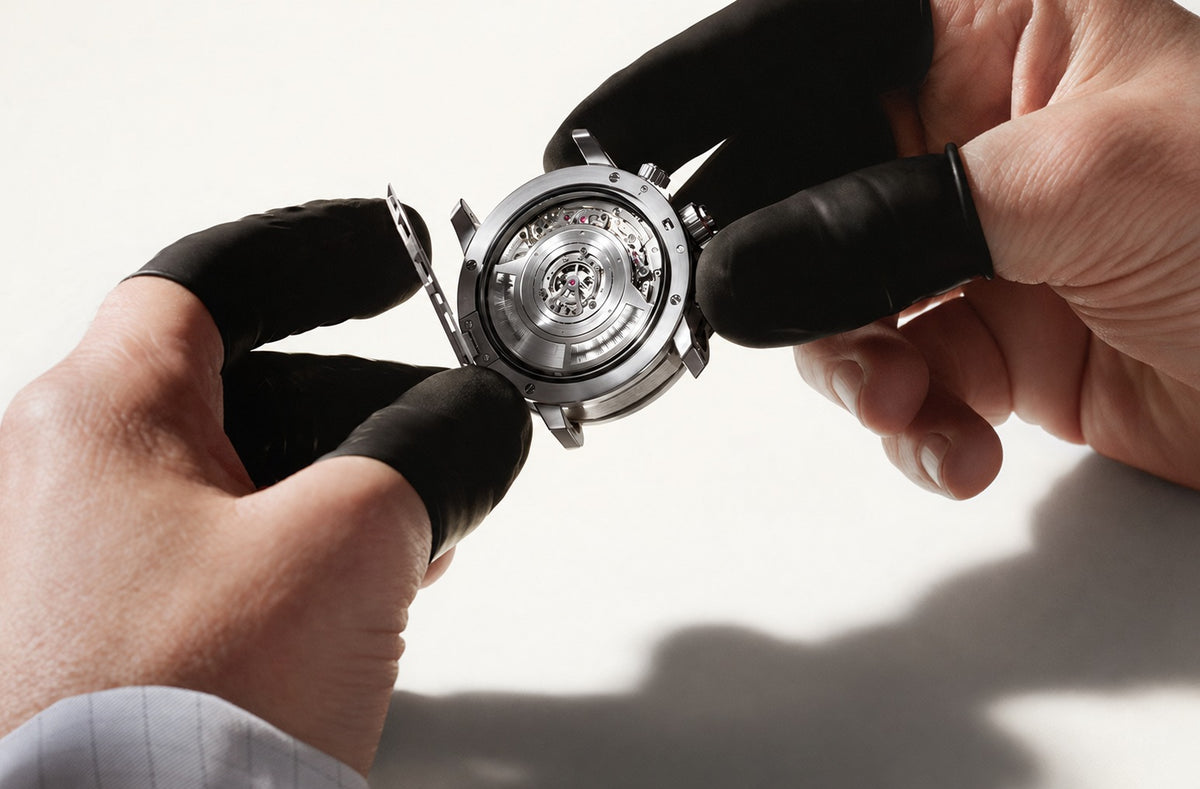 Hands examining a watch movement